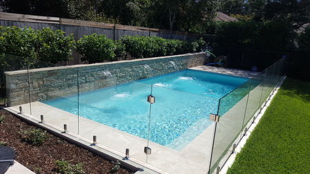light blue pool with stone clad feature wall and 3 fountains